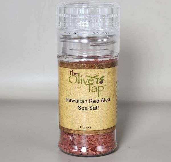 Hawaiian Red Sea Salt in a grinder jar from The Olive Tap with The Olive Tap logo and olive branch against a neutral background.