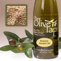 A bottle of The Olive Tap Roasted Sesame Oil next to olives and leaves with an inset showing sesame seeds on a light background.