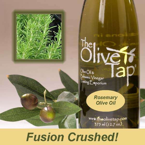 A bottle of Rosemary Olive Oil from The Olive Tap next to olives and leaves with an inset showing fresh rosemary and the words "fusion crushed!" at the bottom of the picture.
