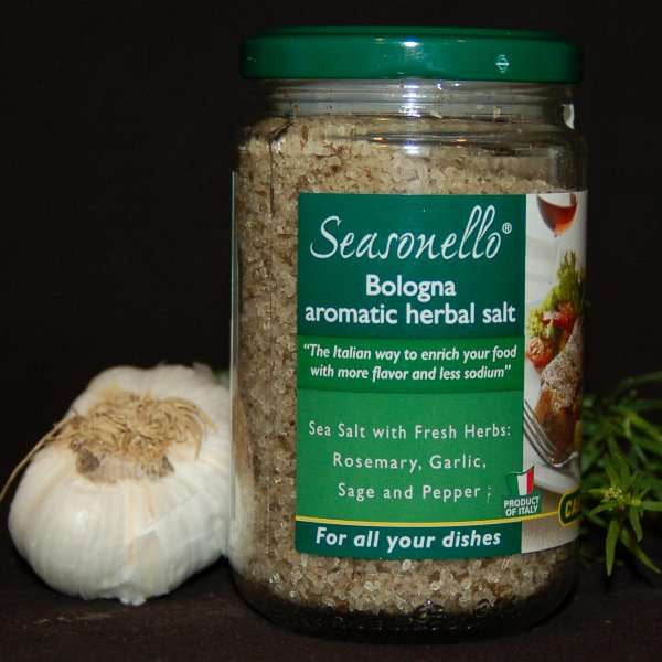 Jar of Seasonello® Herbal Sea Salt, a staff favorite from The Olive Tap, next to fresh rosemary and a bulb of garlic on a black background.