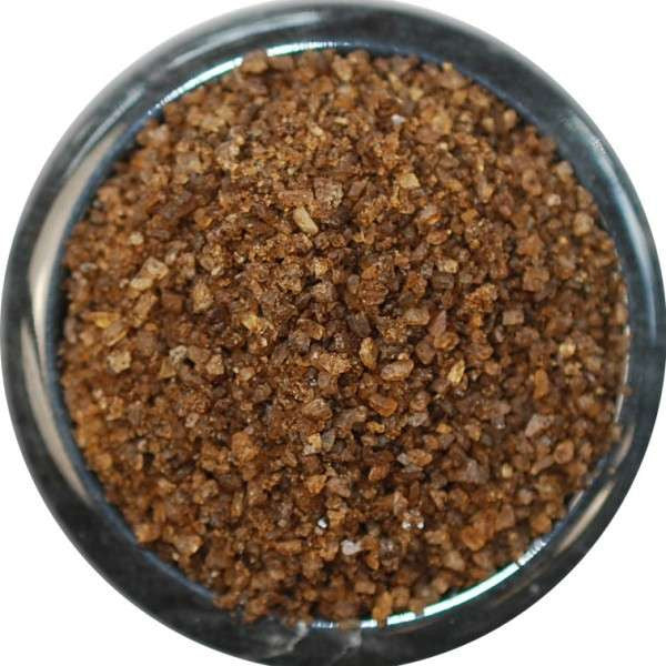 Smoked Bacon Sea Salt from The Olive Tap: Brown pebble-sized chunks of sea salt in a black marble bowl with a white background.