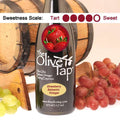 A bottle of Strawberry Balsamic Vinegar from The Olive Tap with a picture of fresh strawberries, surrounded by grapes in front of a wooden barrel, and a sweetness scale indicating a four.