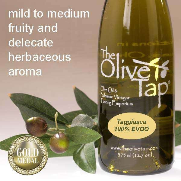 A bottle of Taggiasca 100% Extra Virgin Olive Oil from The Olive Tap with olives and leaves including text describing the olive oil flavor profile on a light background and a stamp with the words "Gold Medal" at the bottom left.