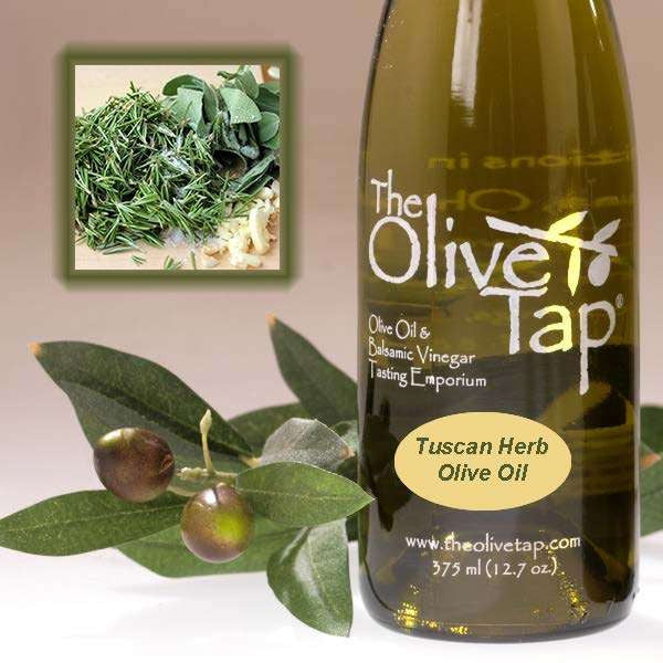 A bottle of Tuscan Herb Olive Oil from The Olive Tap next to olives and leaves with an inset showing fresh herbs.