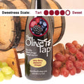 A bottle of Very Berry Balsamic Vinegar from The Olive Tap with a picture of fresh berries, surrounded by grapes in front of a wooden barrel, and a sweetness scale indicating a four.