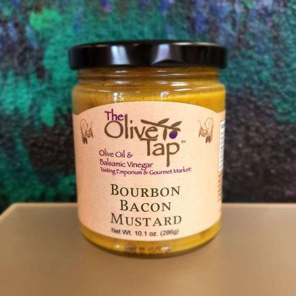 A jar of Bourbon Bacon Mustard from The Olive Tap with a black and turquoise background and placed on a light-colored surface.