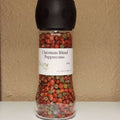 Christmas Blend Peppercorns:  Red and brown peppercorns in a grinder jar from The Olive Tap against a neutral background.