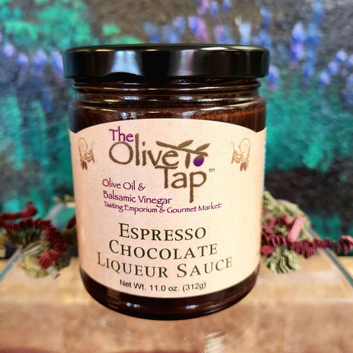 A jar of Espresso Chocolate Liqueur Sauce from The Olive Tap with a colorful background and surrounded by red and green decorative crinkle paper.