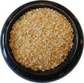 Ghost Pepper Sea Salt from The Olive Tap:  Golden in color pebble-sized sea salt in a black marble bowl with a white background.