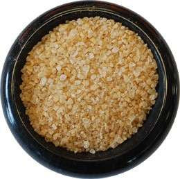Ghost Pepper Sea Salt from The Olive Tap:  Golden in color pebble-sized sea salt in a black marble bowl with a white background.