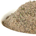 Greek Seasoning from The Olive Tap: A white bowl of ground green herbs with some chunks against a white background.