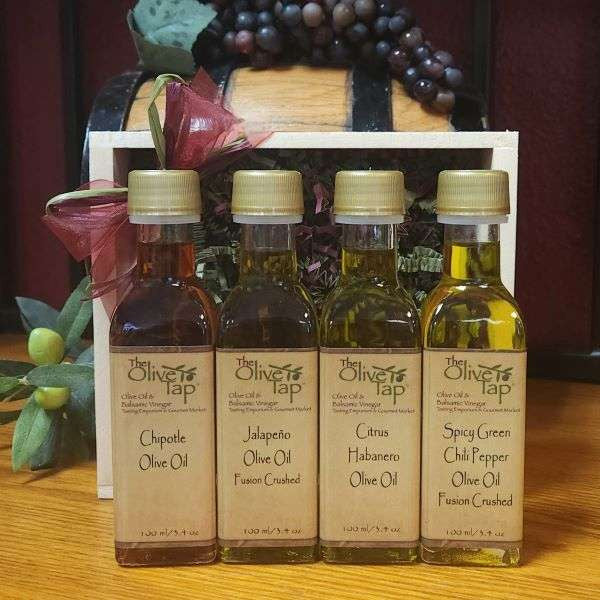 The Hot Pepper Olive Oil Sampler Box: the image displays four bottles of The Olive Tap olive oil in front of a wooden crate.