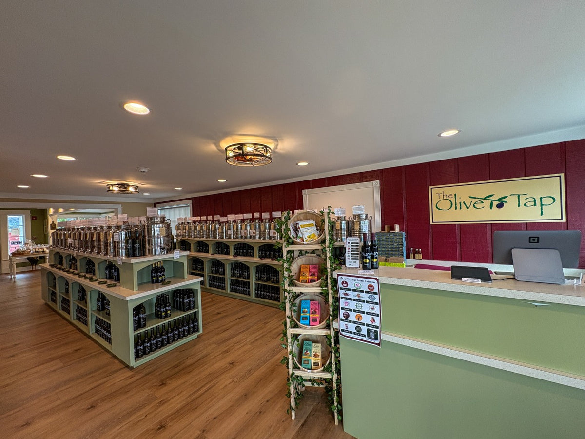 Long Grove Olive Tap store inside with check out counter, cabinets holding rows of stainless steel fusti and Olive Oil and Balsamic Vinegar bottles