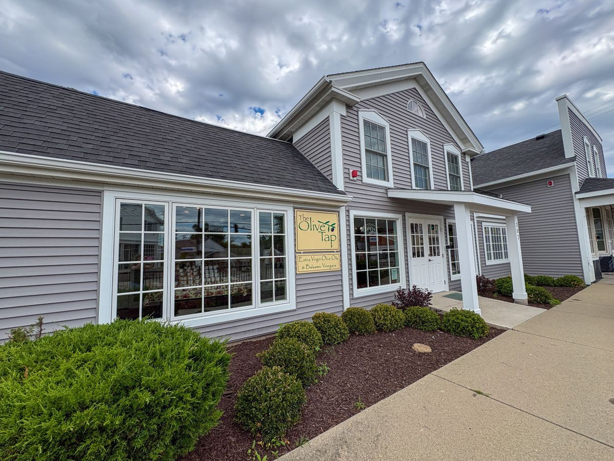 The Long Grove Olive Tap store building. Grey and white with windows and The Olive Tap sign