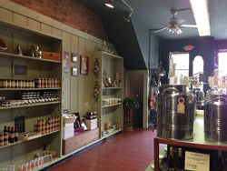 Interior of The Olive Tap Medina store with shelves stocked with bottles and a large metal fusti holding olive oils and balsamic vinegars