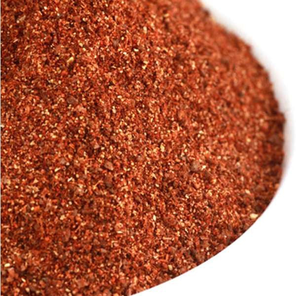 Rick's Backyard Barbeque Rub from The Olive Tap: A white bowl of brownish-red ground spices with speckles of white.