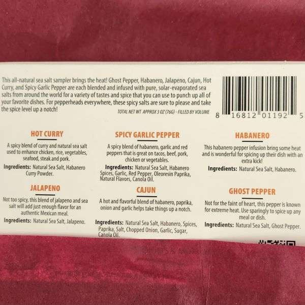 Spicy Sea Salt Sampler from The Olive Tap: Back of the package with a brief description of the spicy sea salts as a whole, and below there are six names of each of the spicy sea salt flavors in orange bold font.  Beneath the names are descriptions and ingredient lists of each of the sea salts.  The package is against a red background.